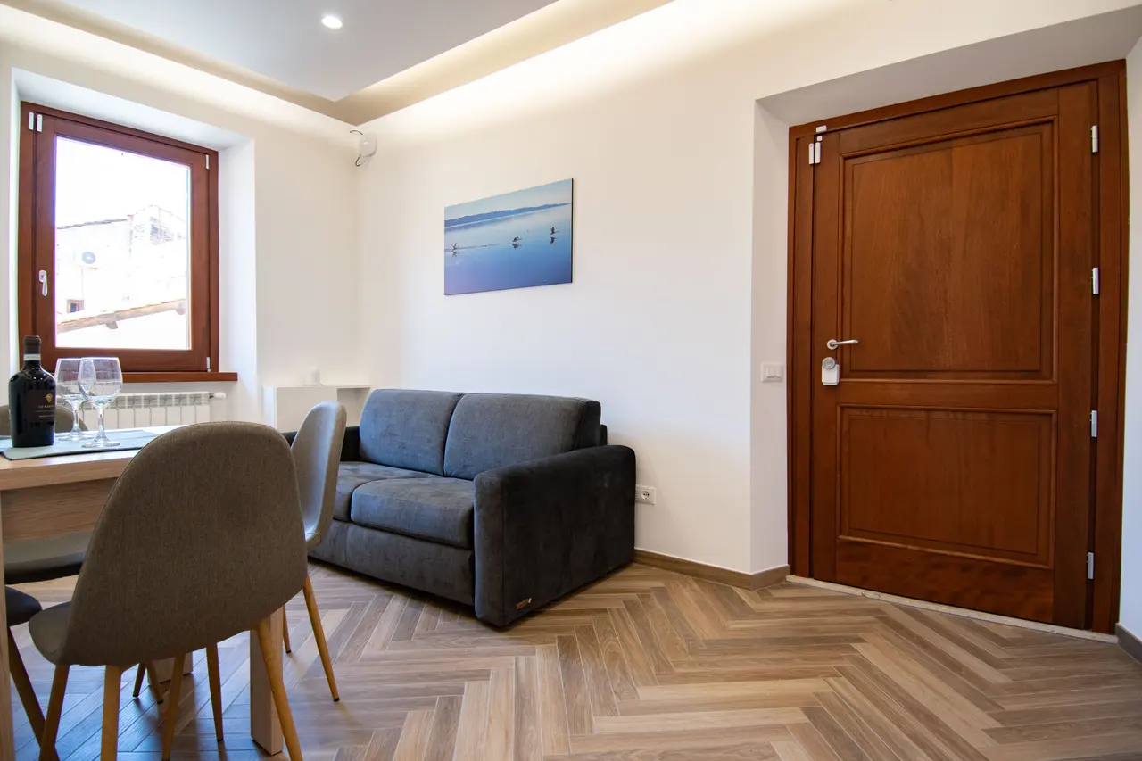 Zona living curata e ben organizzata, con tavolo da pranzo e comodo divano. Luce naturale e atmosfera tranquilla nel cuore del borgo.
